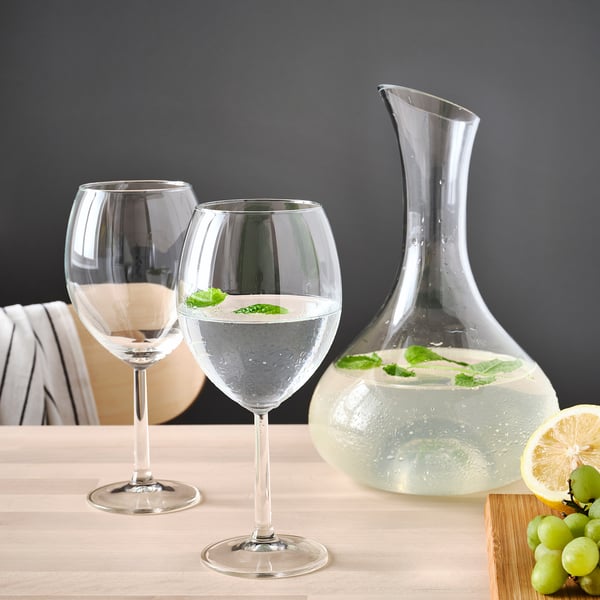 Two wine glasses and a carafe of water with lemon slices on a table.