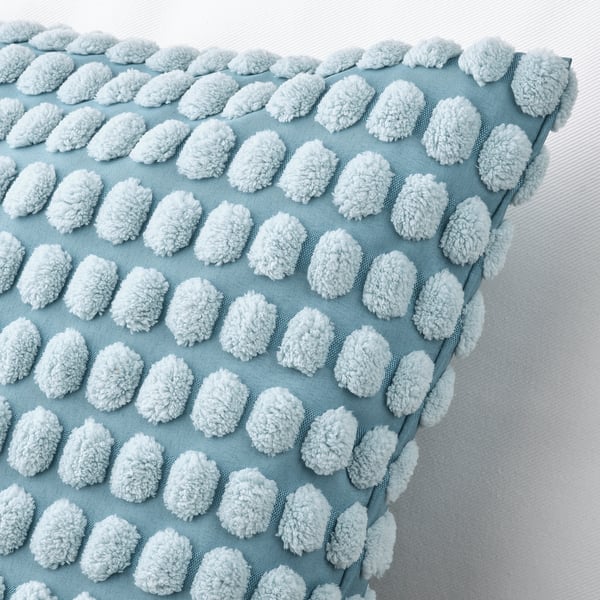 Decorative light blue pillow with soft, white, pom-pom-like accents, neatly arranged in rows, against a white background.