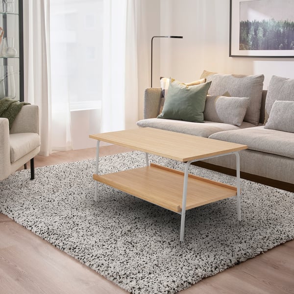 Modern living room with grey & light wood coffee table, patterned rug, matching sofa & curtains.