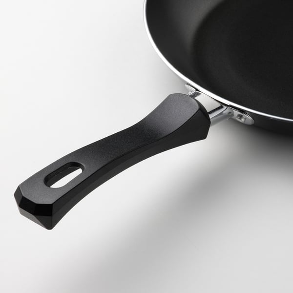 Close-up of frying pan handle, showcasing ergonomic design and robust attachment for secure grip.