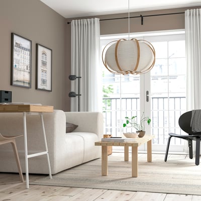 Modern living room with light furniture, TAGGTOFS lamp, and balcony view.