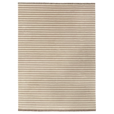 This image shows the TÅGSPÅR rug, a beige and white striped wool rug with a 3d effect.
