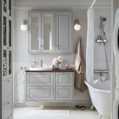 Modern gray bathroom with mirror cabinets, white sink, freestanding tub, semi-recessed basin, wall-mounted vanity, soft lighting, sleek fixtures.