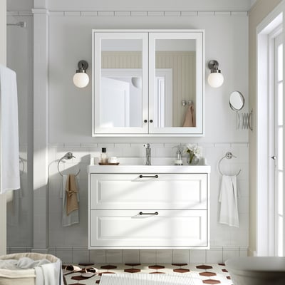 Modern white bathroom vanity with cabinet & mirror. Sink and drawers fit snugly below. Towels hang conveniently nearby.
