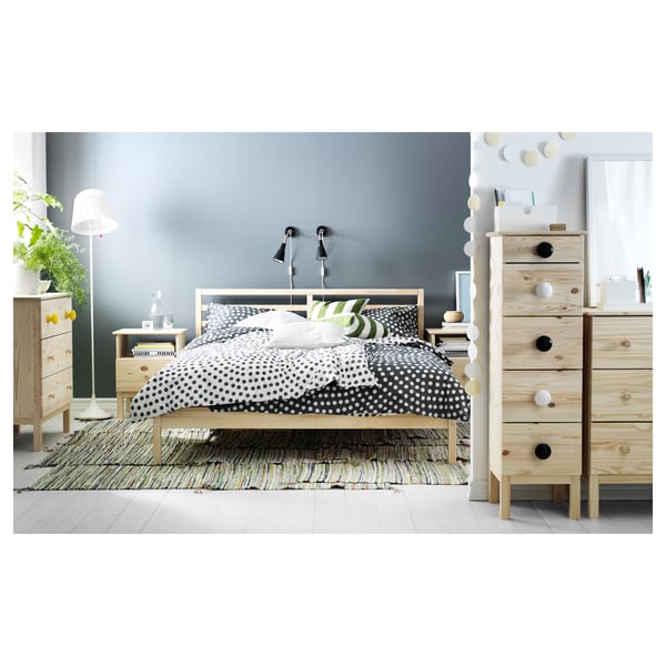 Modern bedroom featuring TARVA bed with polka dot comforter, pine wood furniture, wall lamps, and ambient decor.