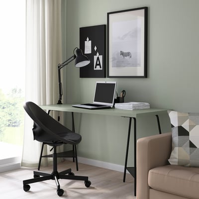 Minimalist desk setup with grey table, black chair, laptop, and decor.