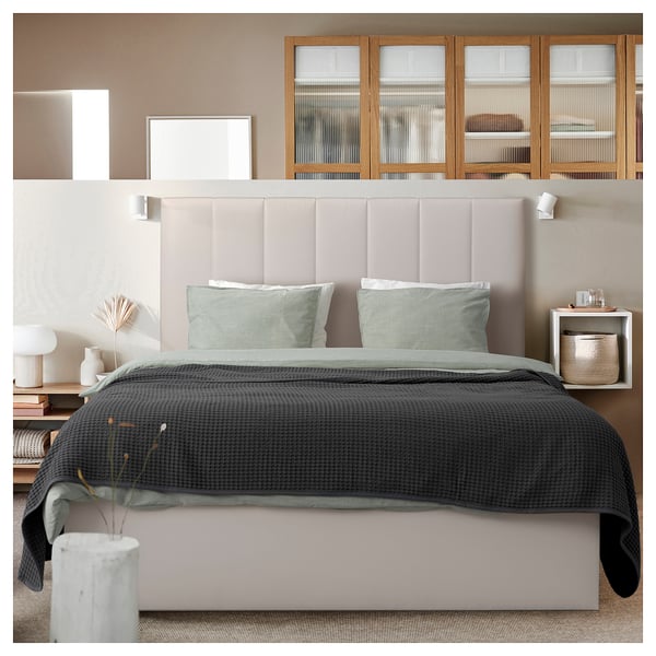 Cozy modern bedroom with TJÅLLE headboard in beige, stunt fabric, rectangle shape, soft padded design, matching bedding, wooden cabinets, walls.