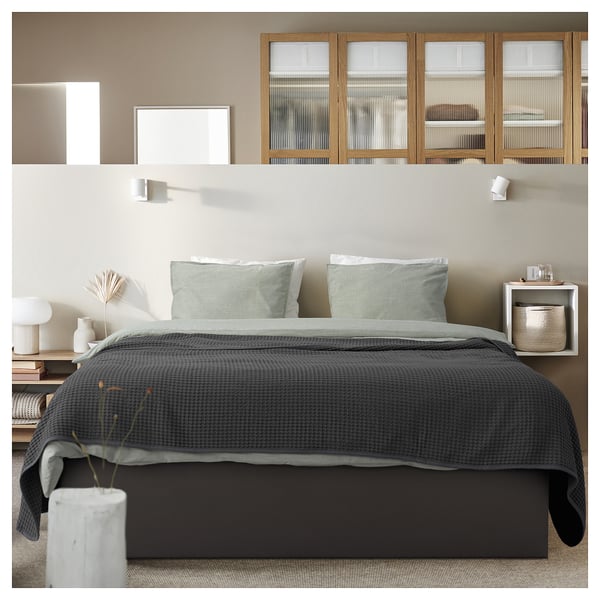 Modern bedroom with TJÅLLE gray bed frame featuring curved headboard, striped pillows, nightstands, and wall-mounted shelves.