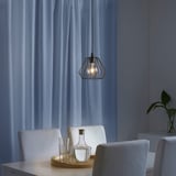 Minimalist TJUGOTRE lamp over dining table with glasses and carafe, warm light.