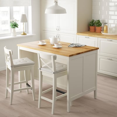 Small white kitchen island with oak top, two stools, in bright kitchen.