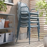 Three blue stackable chairs & shelf on deck. Or, more detailed: stackable blue chairs & metal shelf on wooden deck.