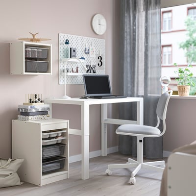 Modern TROFAST desk with storage baskets, books, laptop, and swivel chair.
