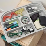 Organized desk tray with items: markers, tape, scissors, cords, mask, keys, sticky notes, and more. Helps sort small items neatly.