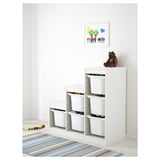 White TROFAST storage unit with multiple bins, perfect for organizing kids toys. A teddy bear is placed on top, and a colorful rug is beneath.