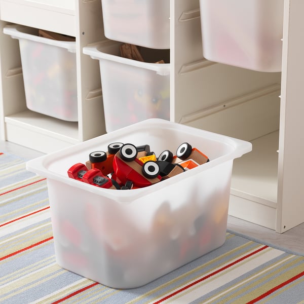 Storage container filled with wooden toys sits on colorful rug, part of TROFAST series.