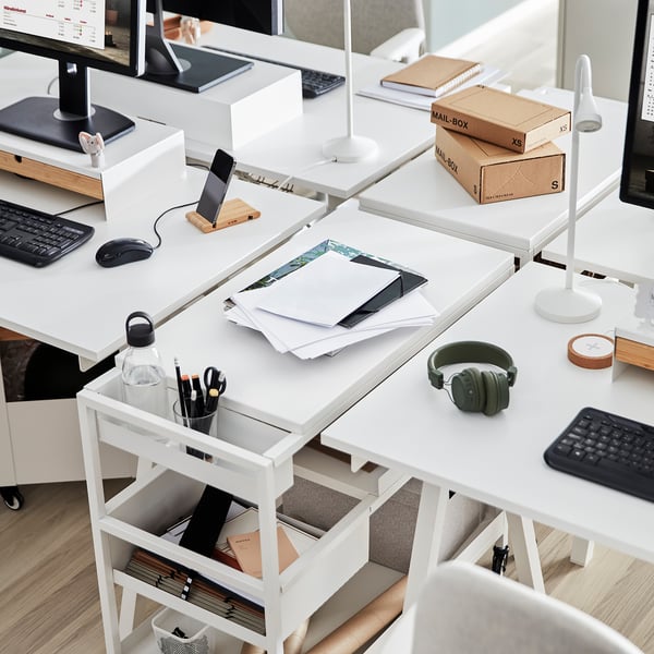 White TROTTEN desk with matching supplies trolley. Organized setup with computers, notebooks, and extra storage.