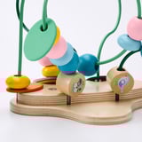Colorful wooden kids toy with green wire frame, featuring beads and leaf shapes, designed to teach shapes and colors.