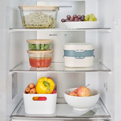 Well-organized fridge shelf with colorful fruits and veggies. Includes storage containers for various foods.