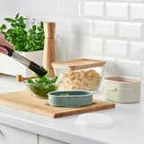 Prepping food on counter. Adding greens to teal lunchbox.