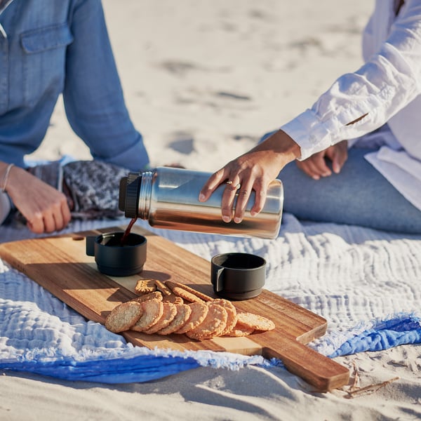 Picnic on beach: two people, coffee, blanket.