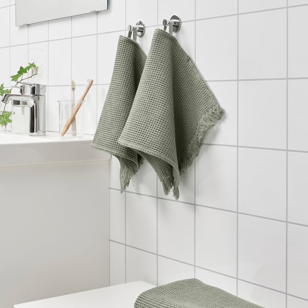 VALLASÅN light green towels hang near sink, soft and absorbent, seen with toothbrush and soap.