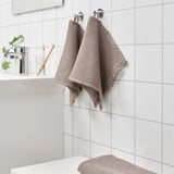 Light brown VALLASÅN towel hangs near sink; smaller than toothbrush holder.