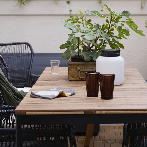 Two brown VARDAGEN glasses on wooden table with other items.