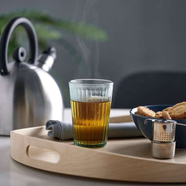 Tray with tea, infuser, cookies, napkin, and kettle.