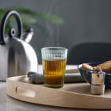 Tray with tea, infuser, cookies, napkin, and kettle.