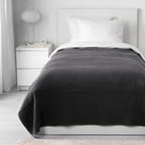 VÅRELD gray cotton bedspread covers a white single bed, larger than bedside drawers.