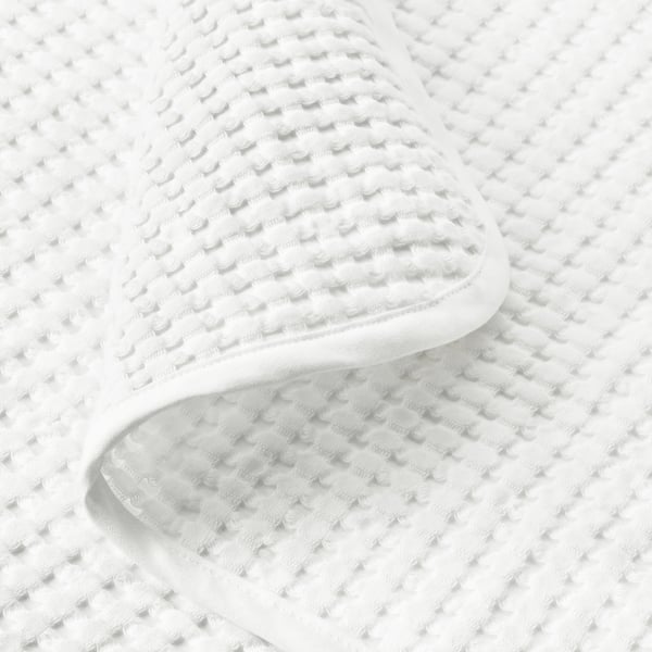 Soft, textured white cotton blanket folded, showing quality weave.