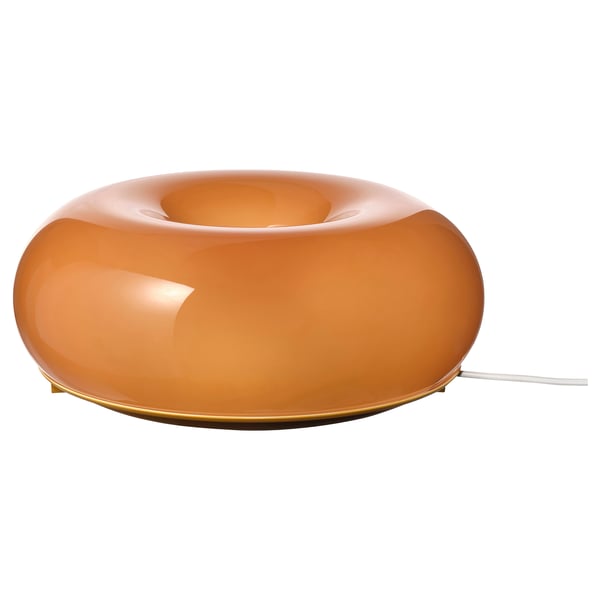 A VARMBLIXT orange glass lamp with a donut shape, featuring a warm glow and a sleek design.