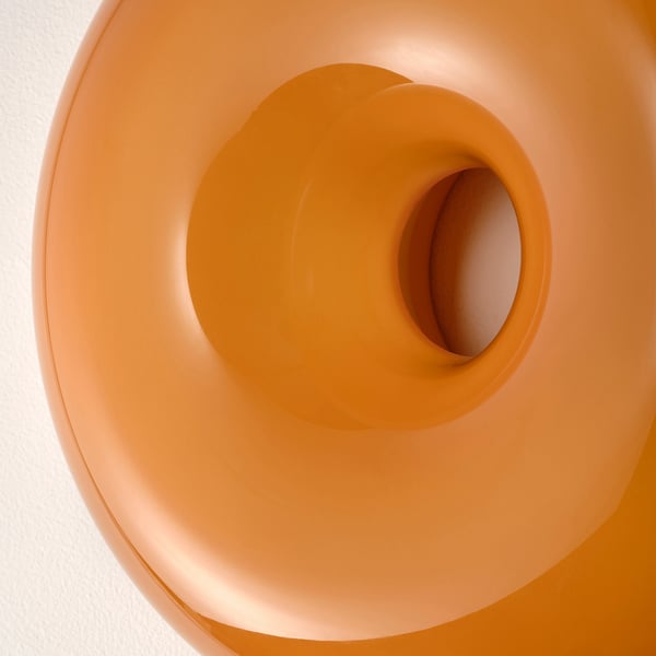A close-up of an orange glass lamp, smooth and round, with a warm, inviting glow.