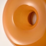 A close-up of an orange glass lamp, smooth and round, with a warm, inviting glow.