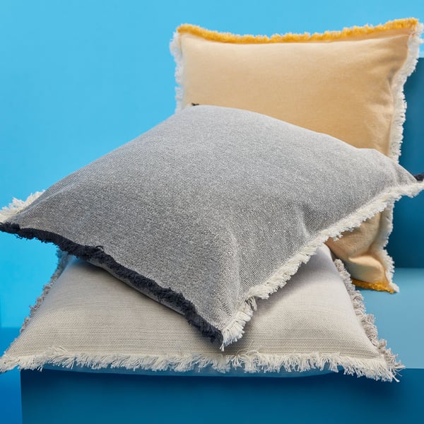 VÄXELBRUK pillow in light gray with white fringe, small size, displayed against bright blue.