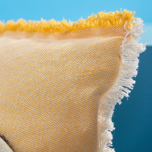 Close-up of VÄXELBRUK cushion cover with yellow-white woven fabric and zipper along one edge.