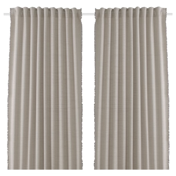 Two beige curtains hang side by side. Made from recycled materials with fringe detailing. Simple, lightweight, and pleated.