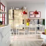 Modern kitchen with wood cabinets, red accents, extendable tables, and large window.