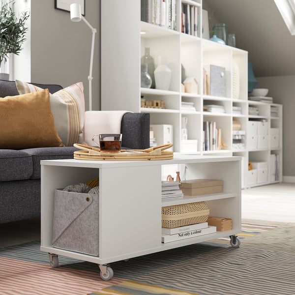 Modern living room with VIHALS coffee table, books, decor, grey couch, and colorful rug.