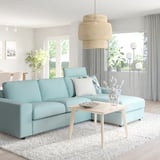 Bright living room with blue VIMLE sectional sofa, wooden coffee table, and wicker pendant lamp. Minimalist decor.