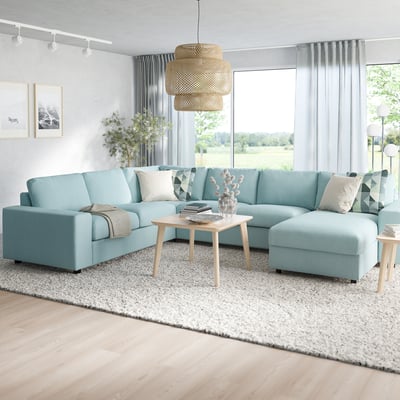 VIMLE blue sectional with chaise, pillows, & hanging light. Wooden coffee table and rug.