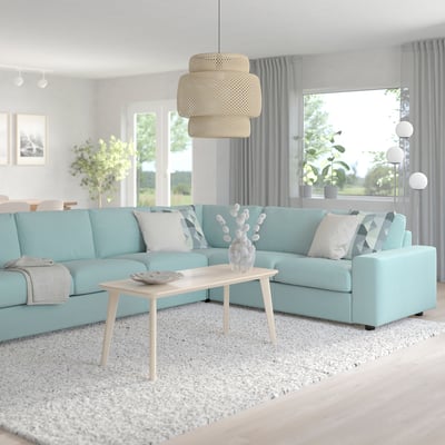 Modern living room with turquoise VIMLE sectional sofa, throw pillows, coffee table, rug, and warm pendant lamp.