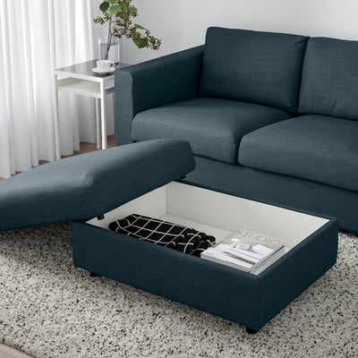 Blue VIMLE sectional sofa with ottoman, white side table, and magazine storage. Modern living room setup.