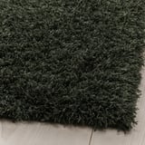 Dark green, soft, thick rug folded on wooden floor.