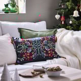 Christmas-themed living room with VINTERFINT black embroidered pillow on white sofa, beside decorated christmas tree.