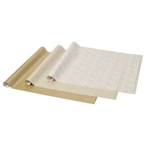Three gold gift wrapping papers with patterns, rolled and fanned out. Solid, stripes, and confetti designs.