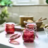 Three red VINTERFINT jars on counter, one open, onions, cutting board.