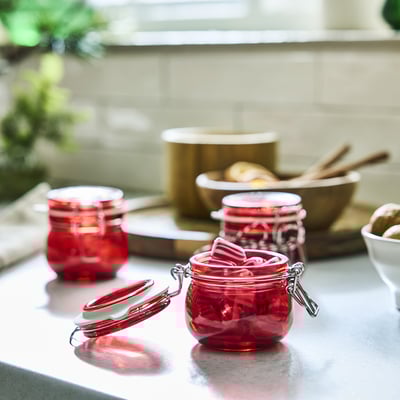 Three red VINTERFINT jars on counter, one open, onions, cutting board.