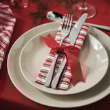 VINTERFINT red and white striped napkin, wrapped with silverware, on white plates, large.