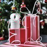 Christmas presents: two wrapped boxes with red paper and white ribbons, one larger box stacked on a smaller one, and a spool of white string on top.